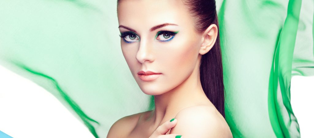 Portrait of young beautiful woman against flying fabric. Beauty woman face closeup. Professional makeup