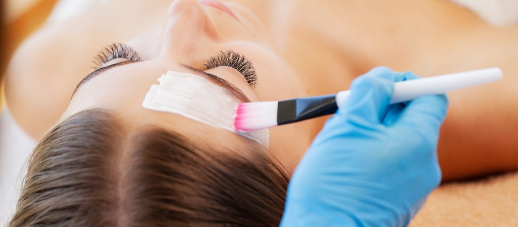 Woman getting facial care by beautician at spa salon.