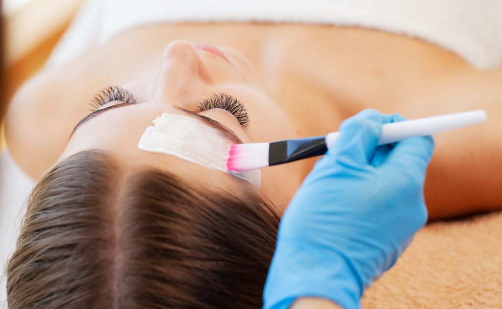 Woman getting facial care by beautician at spa salon.